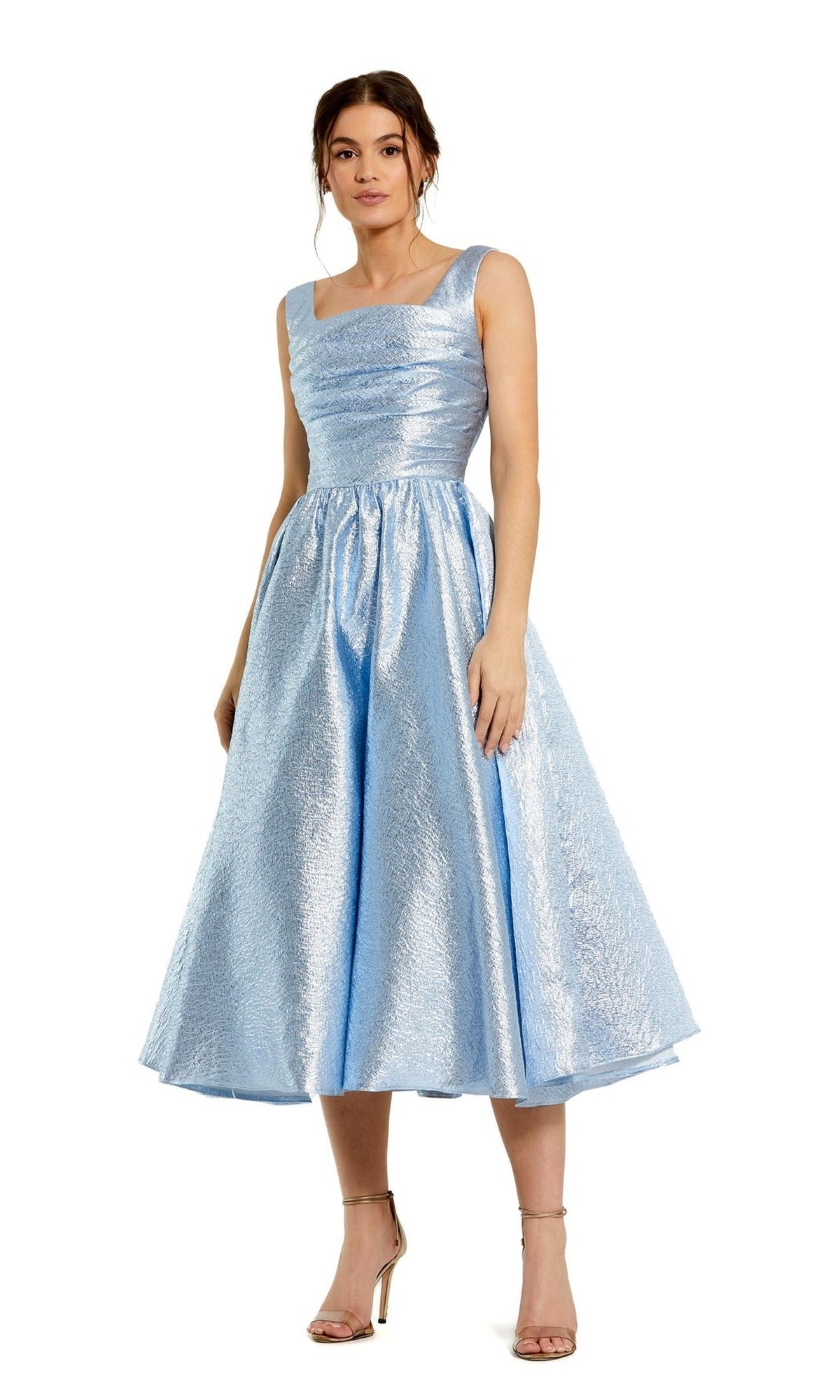 Woman wearing the Mac Duggal 68350 tea-length sleeveless A-line dress in light blue with a textured fabric and square neckline, paired with nude heels—an elegant wedding-guest dress option against a white background.